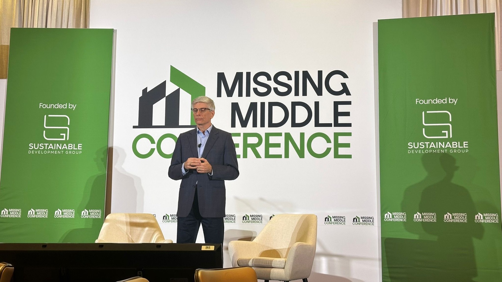 David Babakaiff, Co-Founder of VanPlex, presenting on the main stage at the 2026 Missing Middle Conference at Fairmont Pacific Rim, with a slide showing new multiplex sale prices per square foot across Vancouver West, City of North Vancouver, Vancouver East, Burnaby, and Kelowna